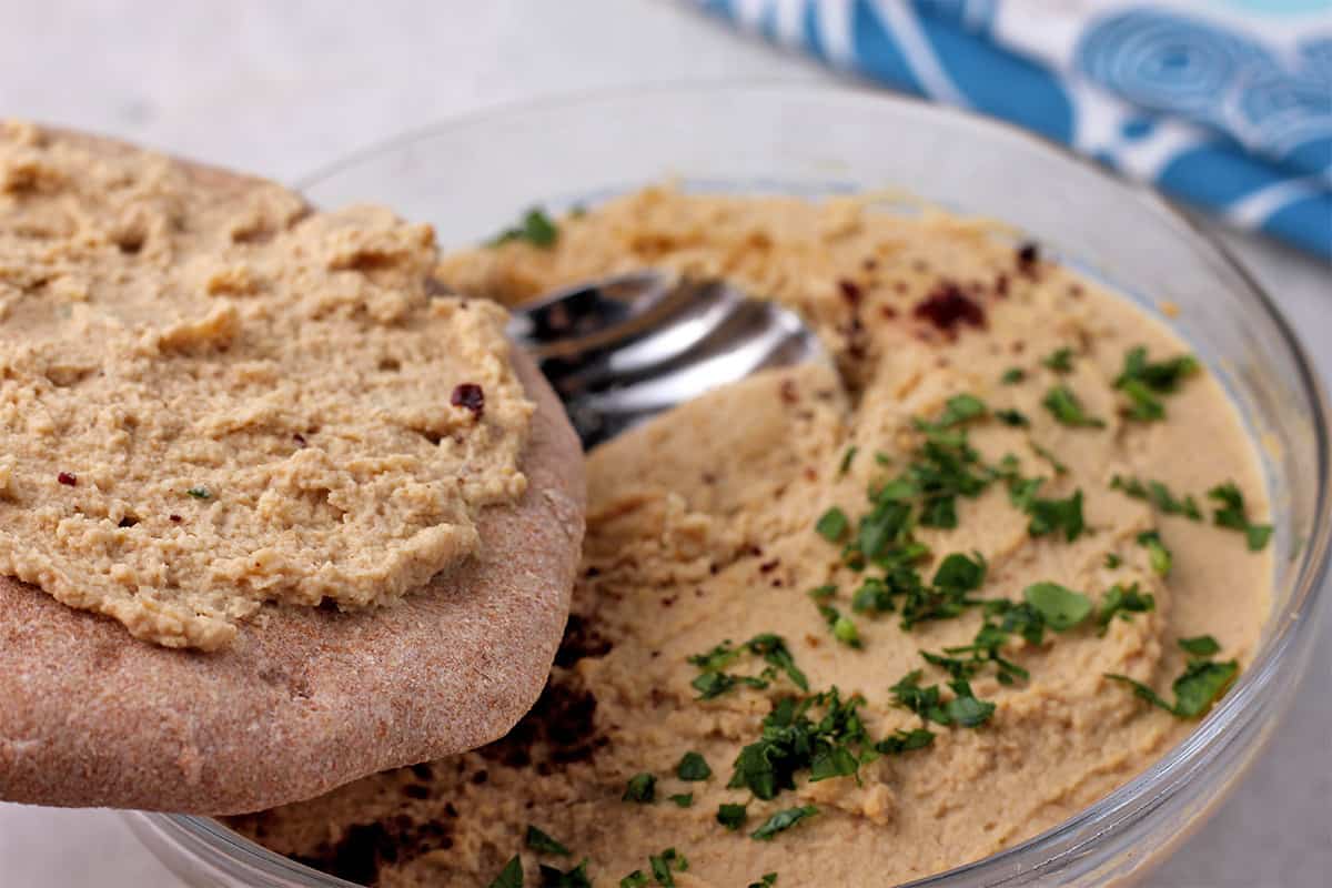 A whole wheat pita is smeared with chickpea hummus.