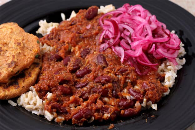 Rajma masala is served over rice and served with pickled red onions and sweet potato flatbread.