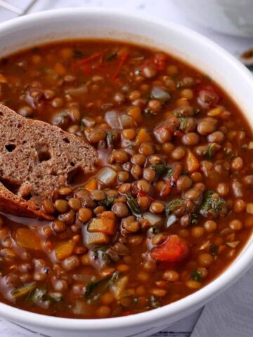 Wheat bread is dipped into vegan French Lentil soup.