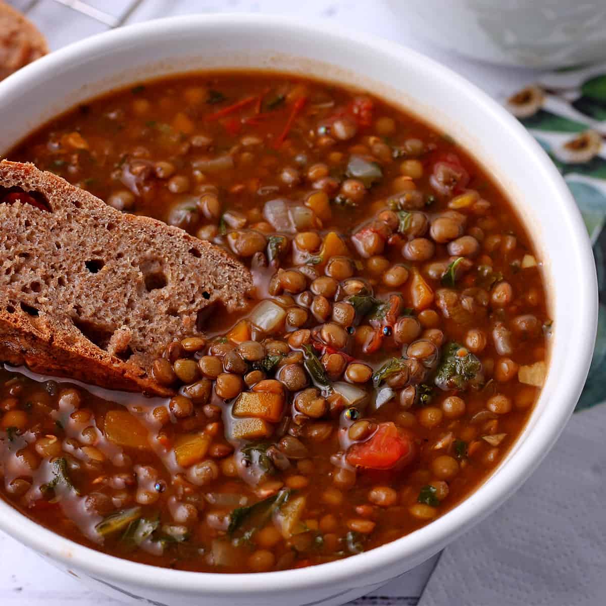 Wheat bread is dipped into vegan French Lentil soup.