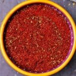 Overhead of homemade chili powder in a yellow bowl with recipe title.