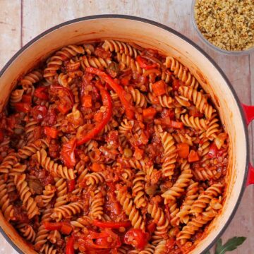 Cooked pasta is made with lentils cacciatore with capers, tomatoes, and red pepper slices.