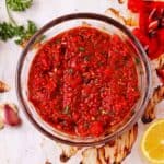 red pepper harissa paste with lemon, garlic, and parsley in glass bowl.