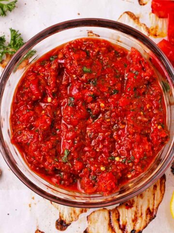 red pepper harissa paste with lemon, garlic, and parsley in glass bowl.