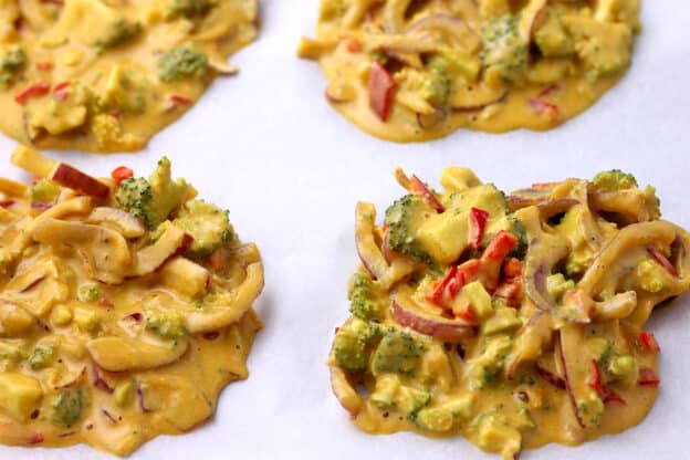 Pakoras with broccoli, red onion, red chili, and chickpea batter are placed on a tray before baking.