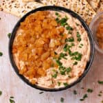 A bowl is filled with vegan French onion dip with caramelized onions and chopped chives.