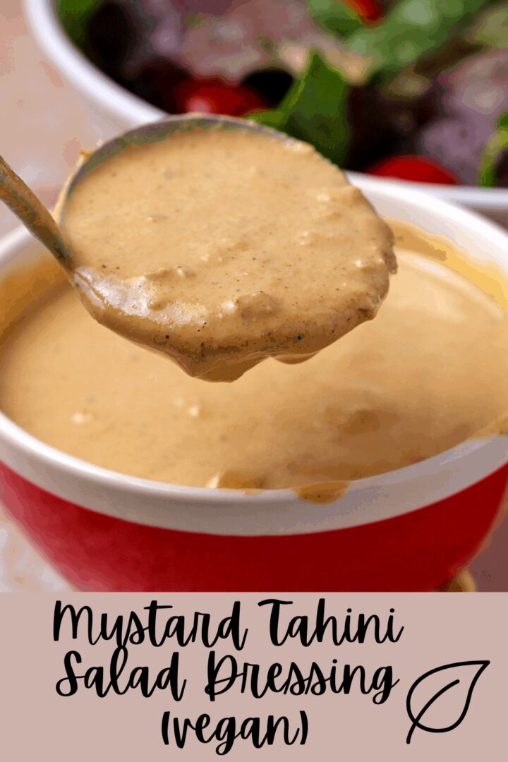 A ladle with mustard tahini dressing over a red bowl.
