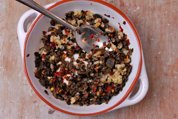 A dish of chopped black olives, minced garlic, lemon juice, and red chili flakes.
