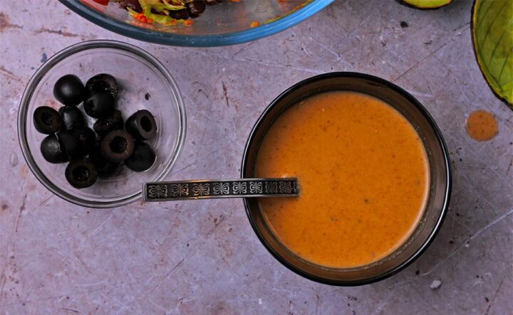 A bowl of chipotle salad dressing with a small ladle.