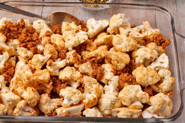 A baking dish with raw cauliflower and tofu sausage crumbles.