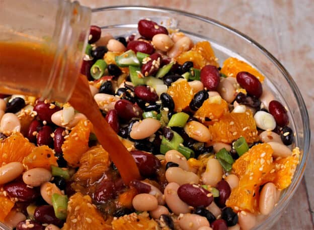 A dressing with orange juice and soy sauce is poured over 3-bean salad.