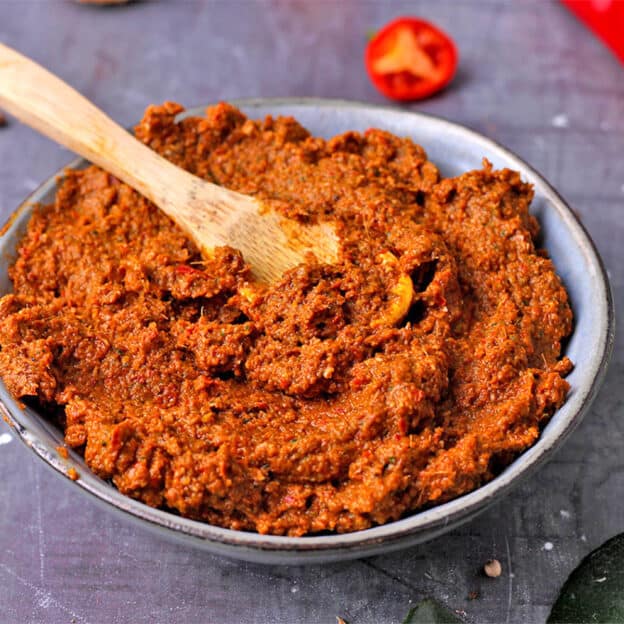 Vegan Thai red curry paste in a small bowl with a wooden spoon.