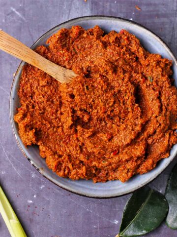 Thai red curry paste in a bowl with a small wooden spoon.