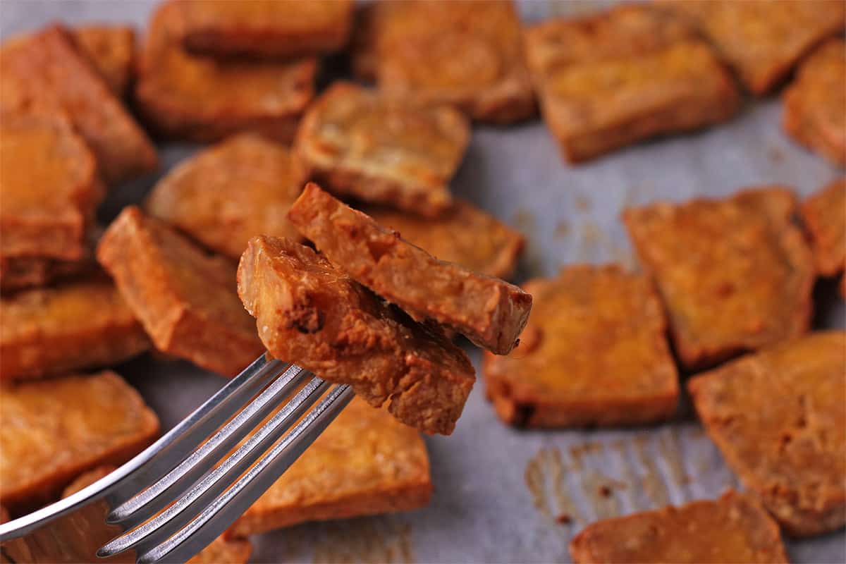 2 pieces of baked tofu on a fork.