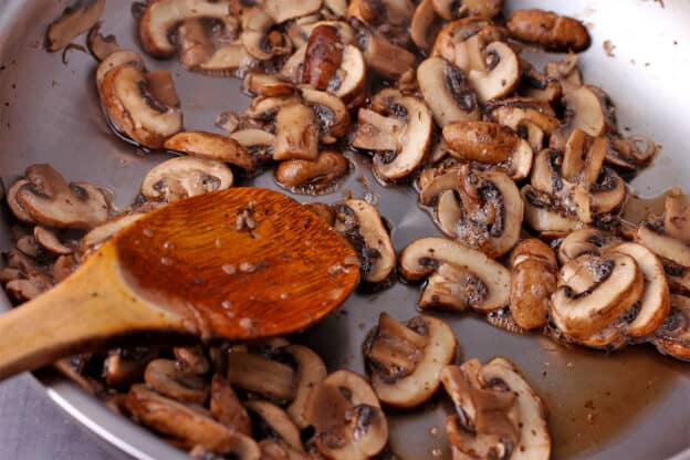 Mushrooms are fried in a skillet.
