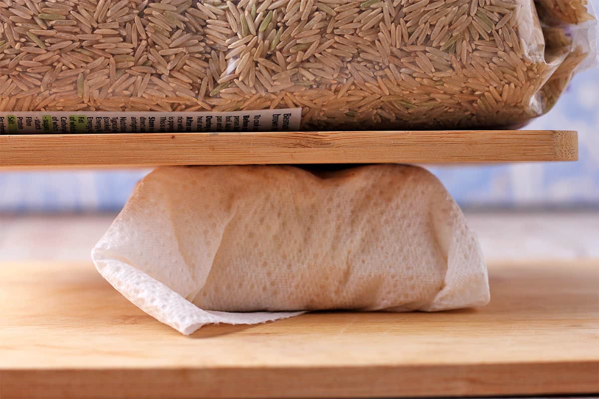 Tofu is pressed between two cutting boards.
