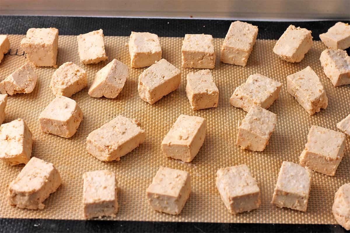 Tofu cubes are placed on a silicone mat before baking.