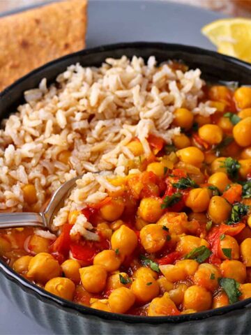 Chana masala in a bowl with rice and a spoon.