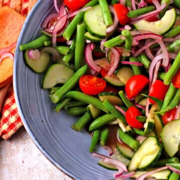 Green bean salad with cucumbers, red onions, and tomatoes in a balsamic dressing.