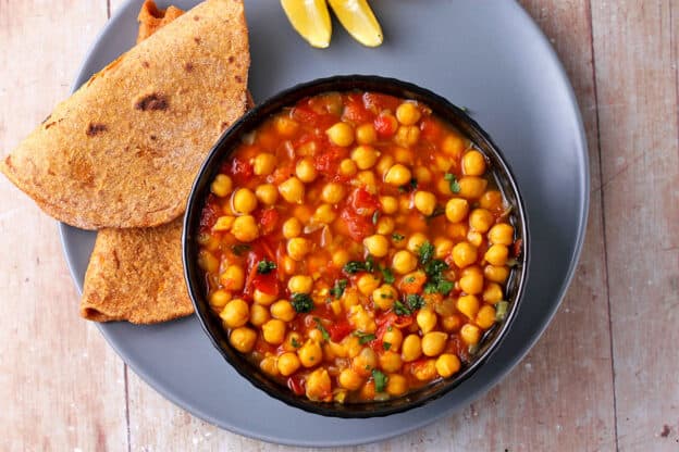 Overhead shot of a bowl filled with chickpea curry with flatbread.