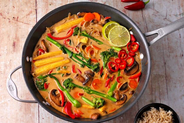 A wok with cooked vegetable curry in Thai red sauce.