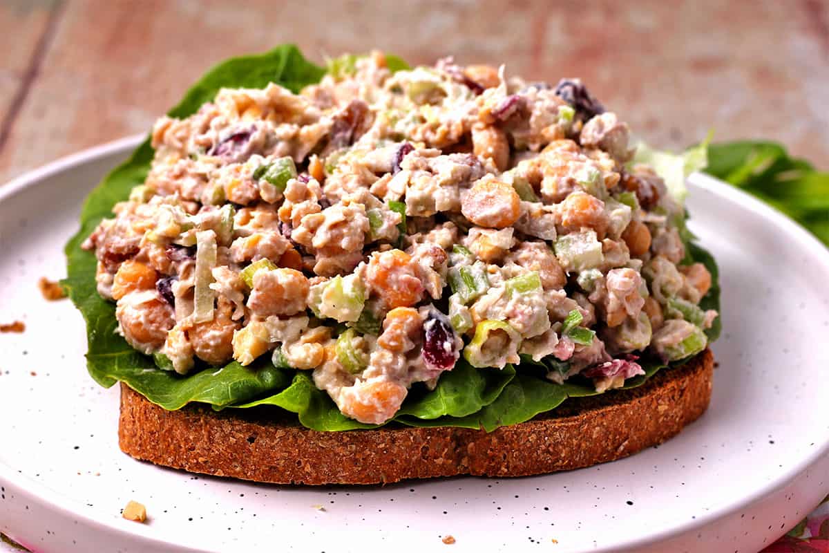An open-faced sandwich with lettuce and chickpea salad with cranberries, walnuts, scallions, and celery.