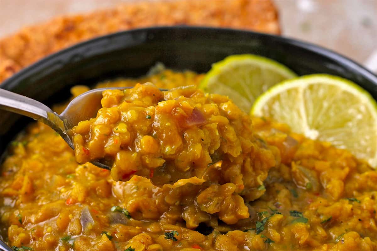 Fresh mango dal with red lentils in a bowl with a spoon.