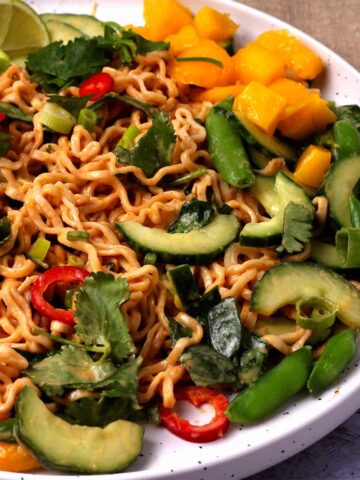 Salad with cucumber, mango, noodles, chili, spinach, and cilantro with peanut sauce.