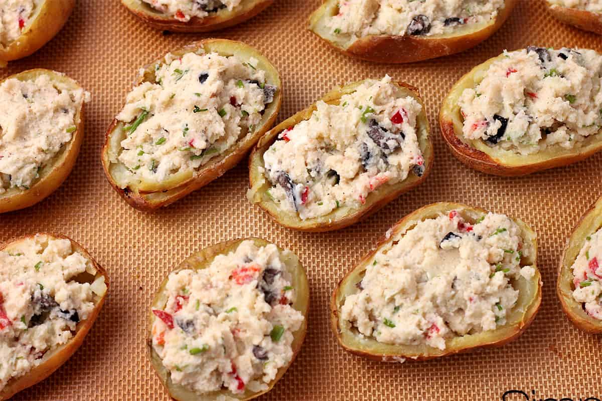 Potato skins are stuffed with mashed potatoes, chives, black olives, and red chili.