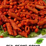Pasta is mixed with red pesto and topped with seasoned chickpeas and served over arugula.