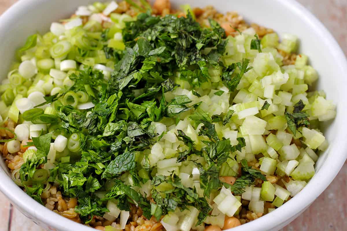 mint, celery, parsley, and scallions are added to cooked freekeh and chickpeas.