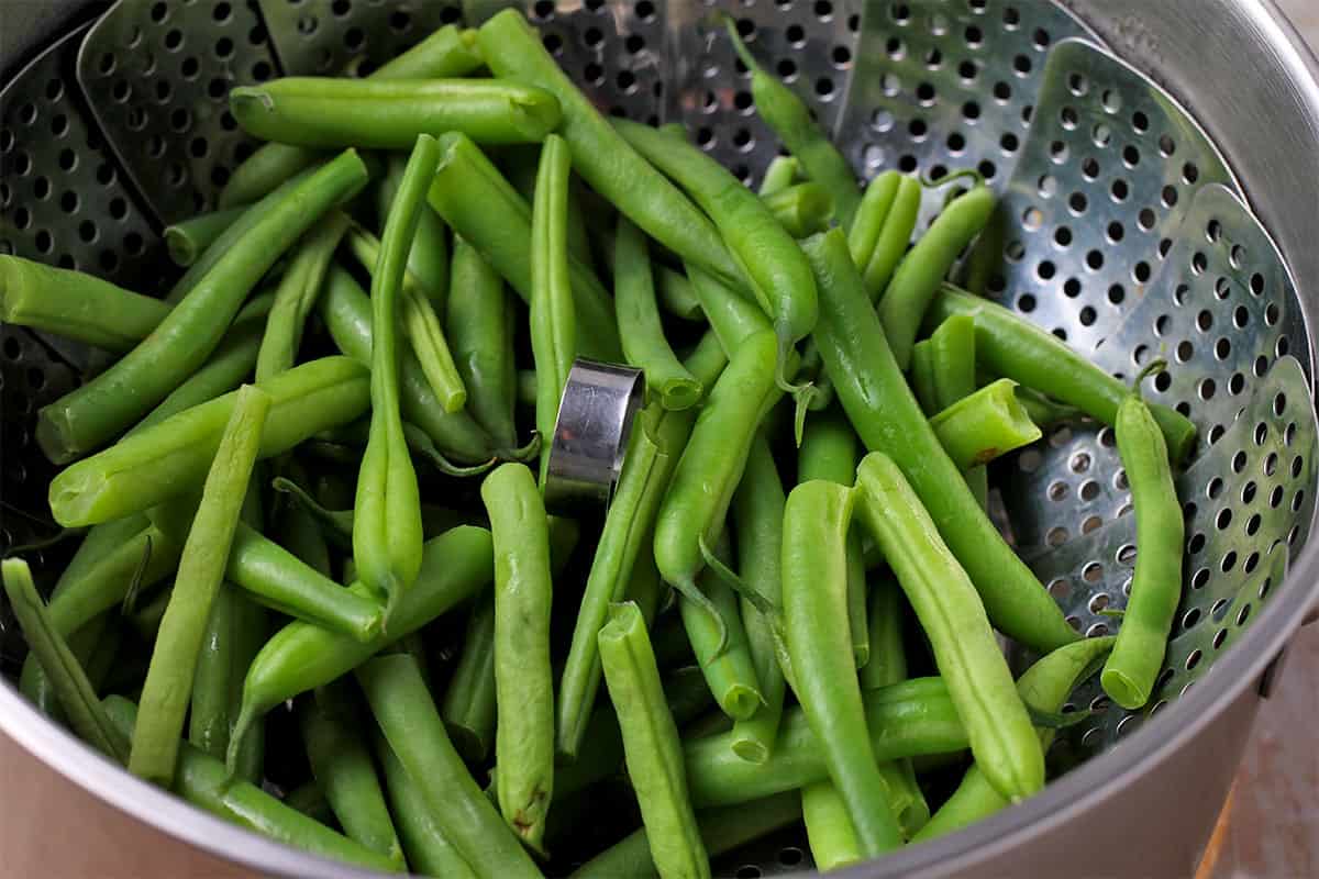 Green beans are steamed in a basket.
