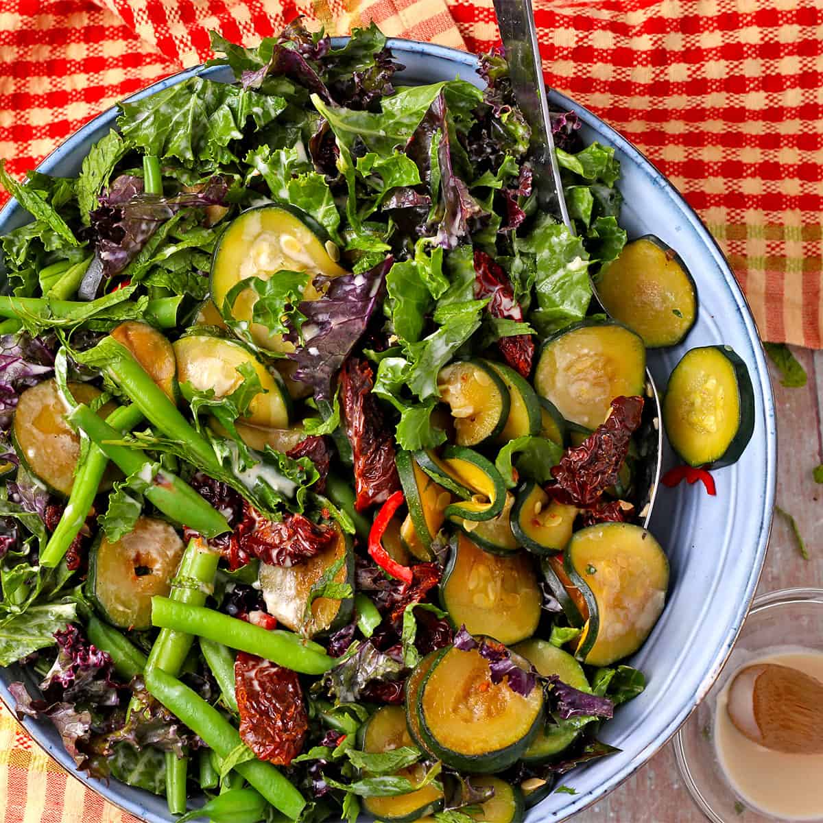 A salad with green beans, zucchini, sundried tomatoes and kale with tahini dressing.