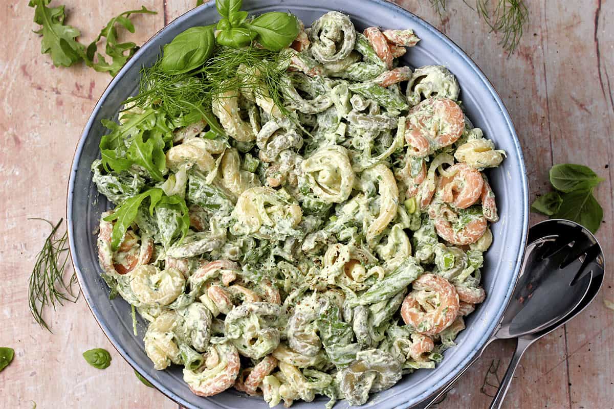 A blue bowl filled with vegan pasta salad with green goddess dressing.