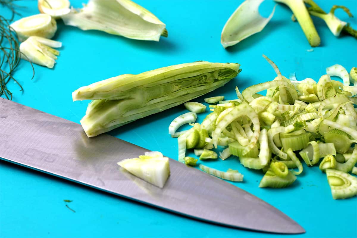 A fennel bulb is sliced using a chef's knife.