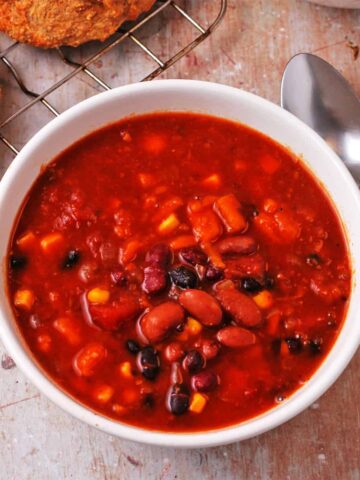 A white bowl filled with chili with beans, corn, and sweet potatoes.