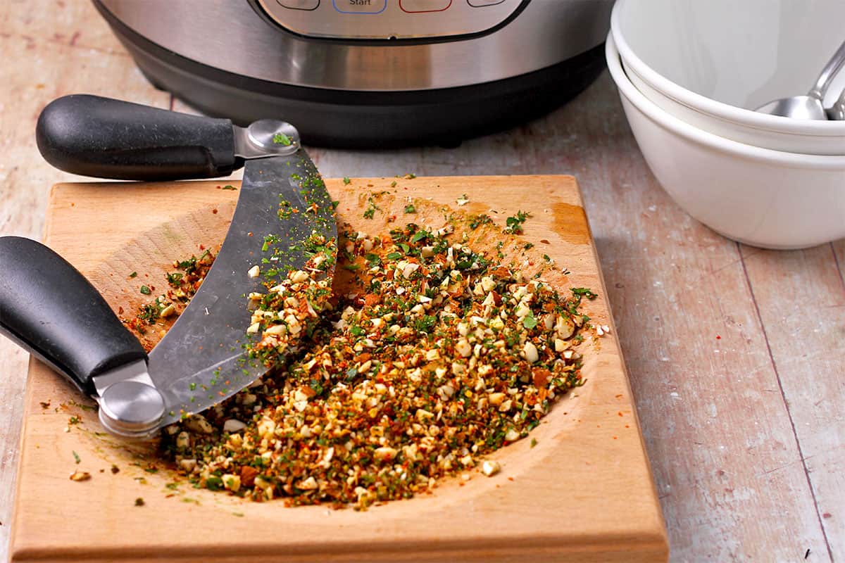 Chopped almonds, red chili flakes, and parsley on a board.