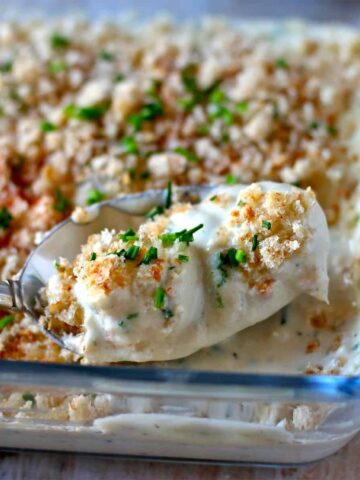 Pearl onions in vegan cream sauce in casserole dish with breadcrumbs and chives.