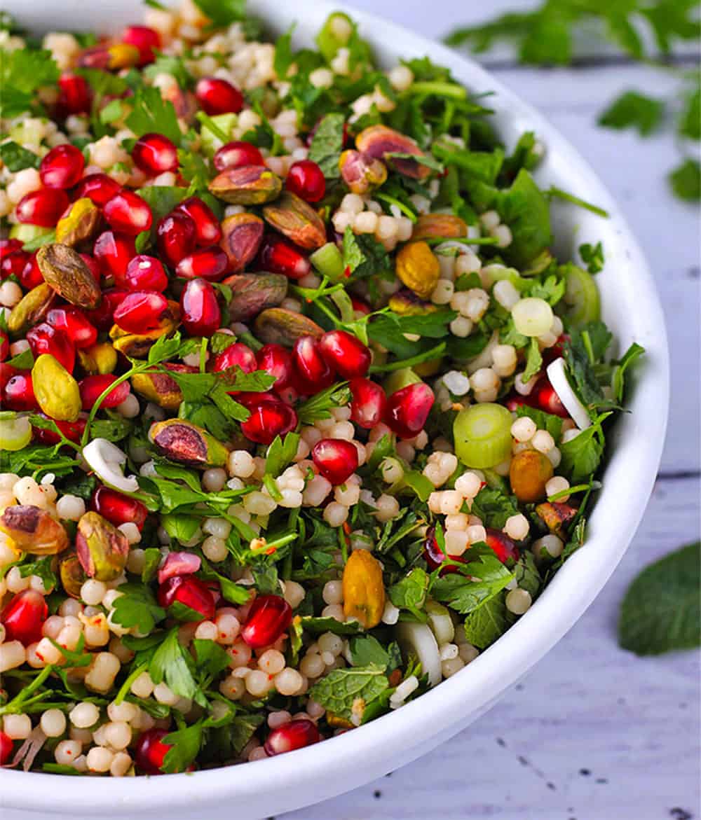 Pomegranate salad with pearl couscous, herbs, pistachios, and scallions.