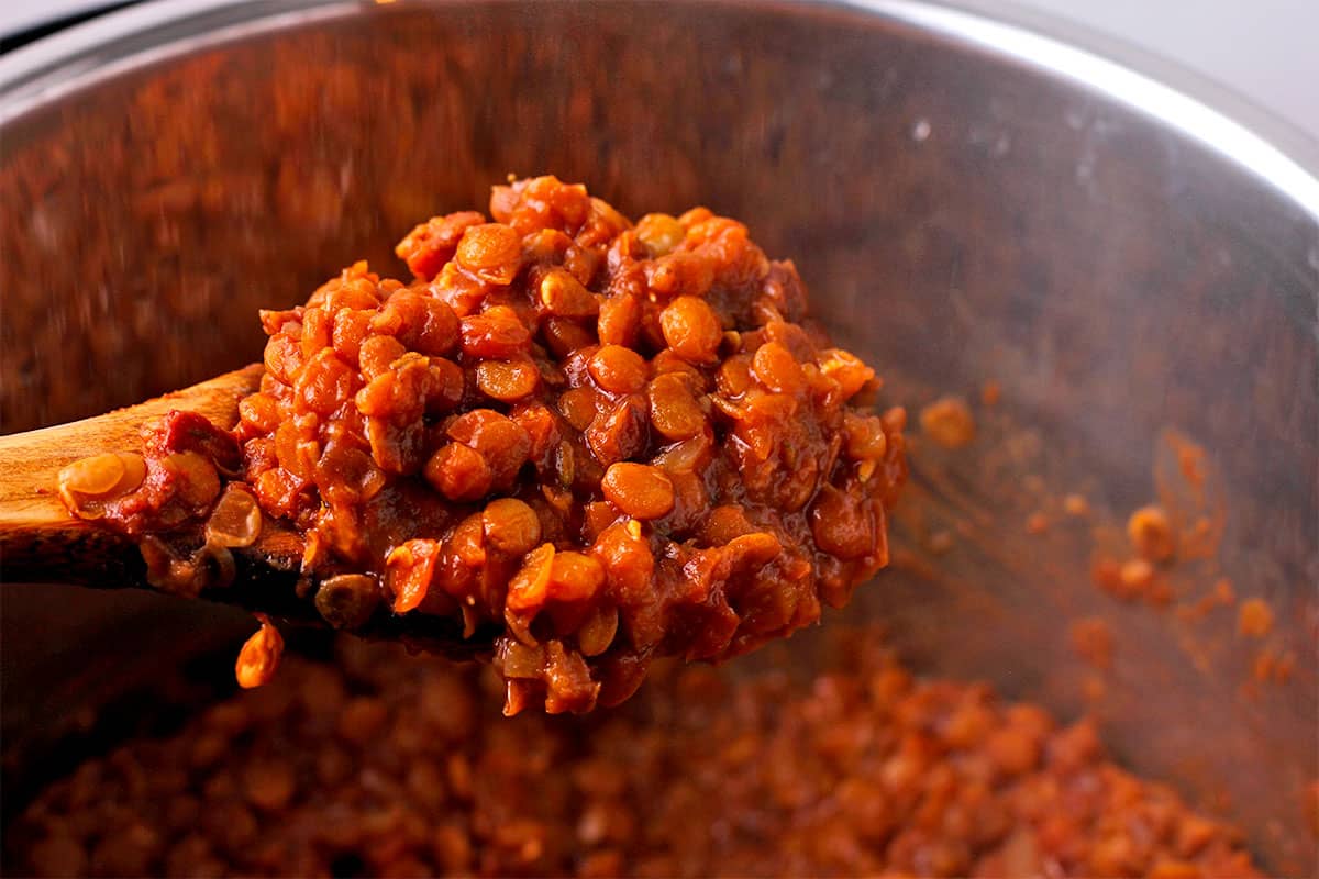 Lentils in tamarind sauce in a wooden spoon in the Instant Pot.