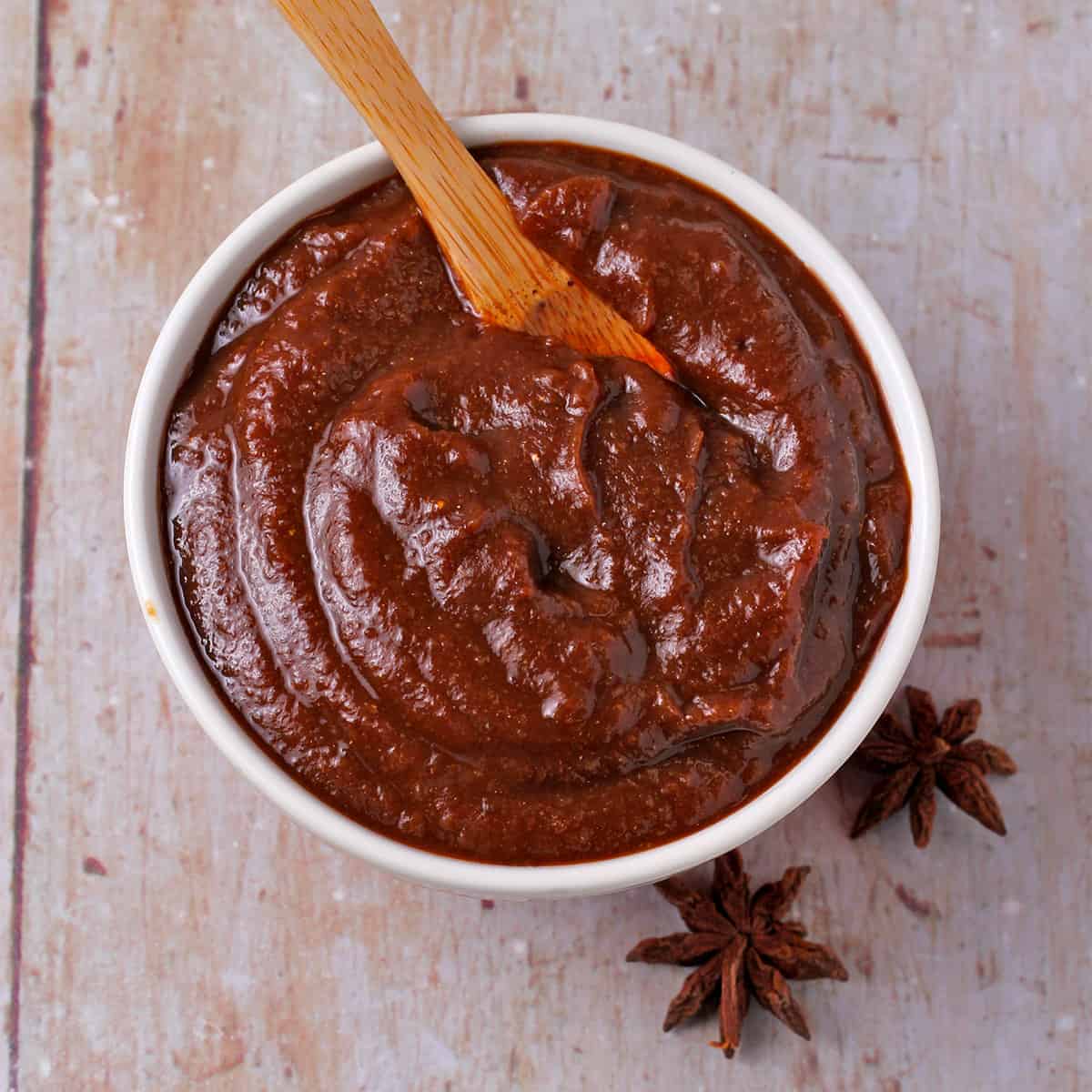 Vegan hoisin sauce in a bowl with 2 star anise on the board beside it.