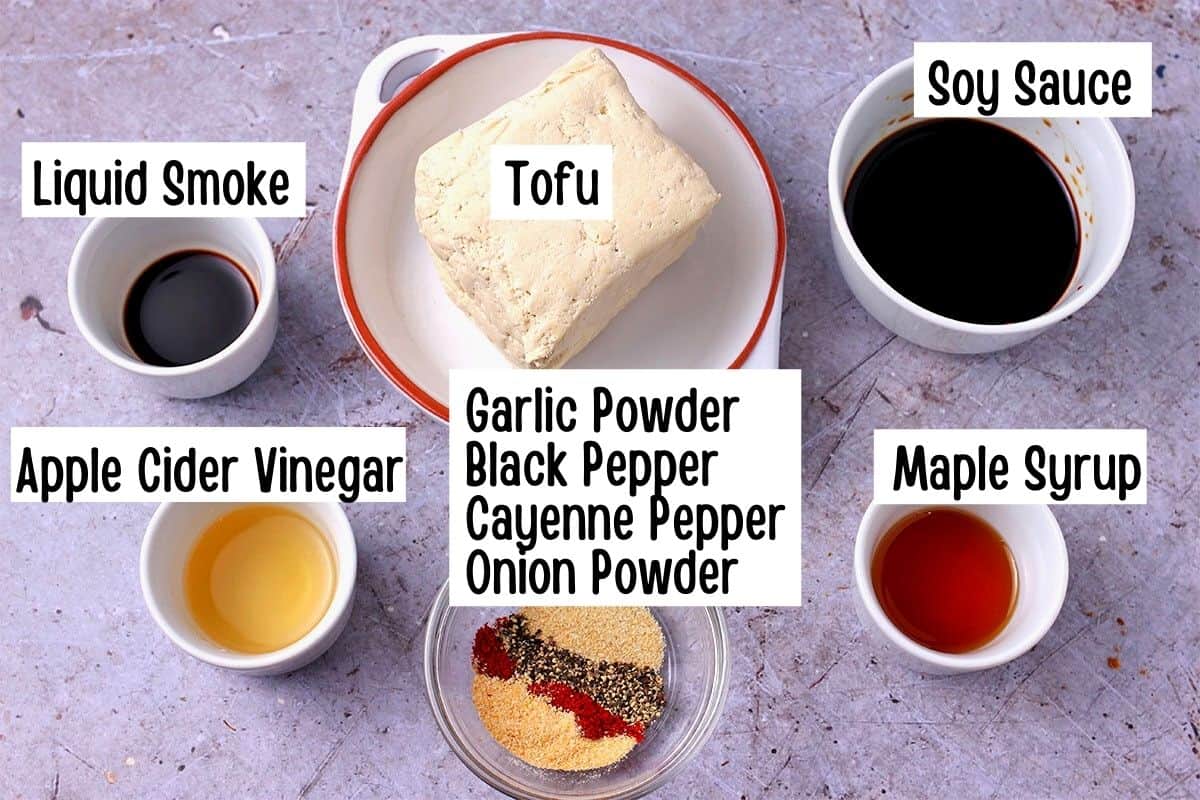 The ingredients for tofu bacon: Tofu, soy sauce, liquid smoke, apple cider vinegar, maple syrup, garlic powder, onion powder, black pepper, cayenne pepper.