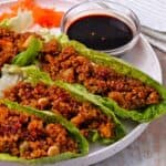 Vegan lettuce wraps with bulgur and firecracker dipping sauce on a white plate.