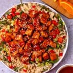 Vegan orange tofu is served with rice and vegetables.