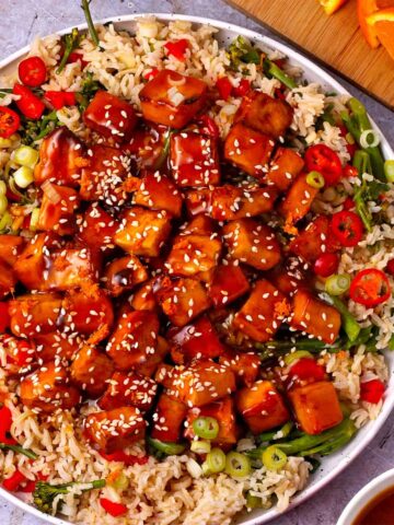 Vegan orange tofu is served with rice and vegetables.