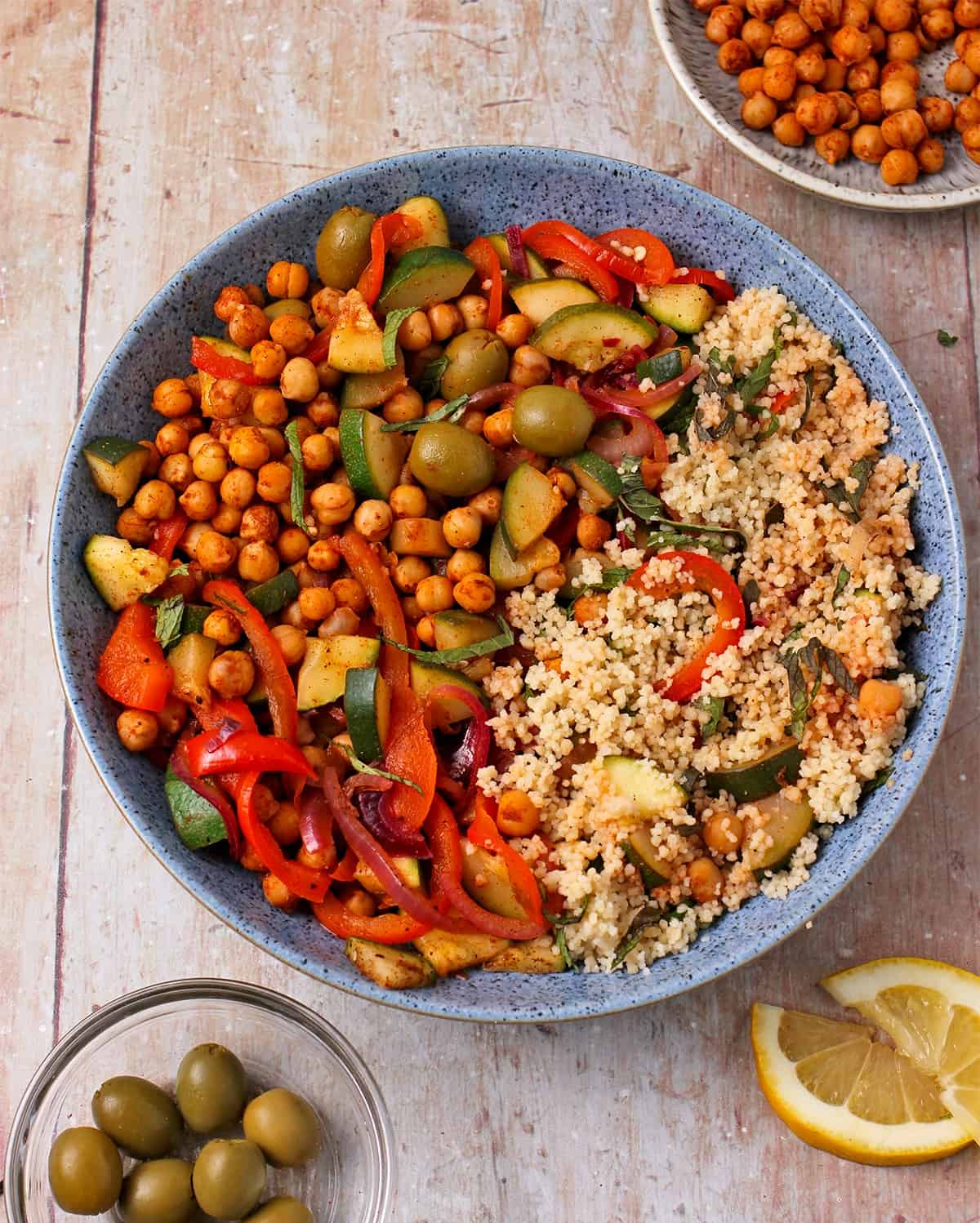 A bowl of chickpea, veggie, and couscous salad with fresh mint and green olives.