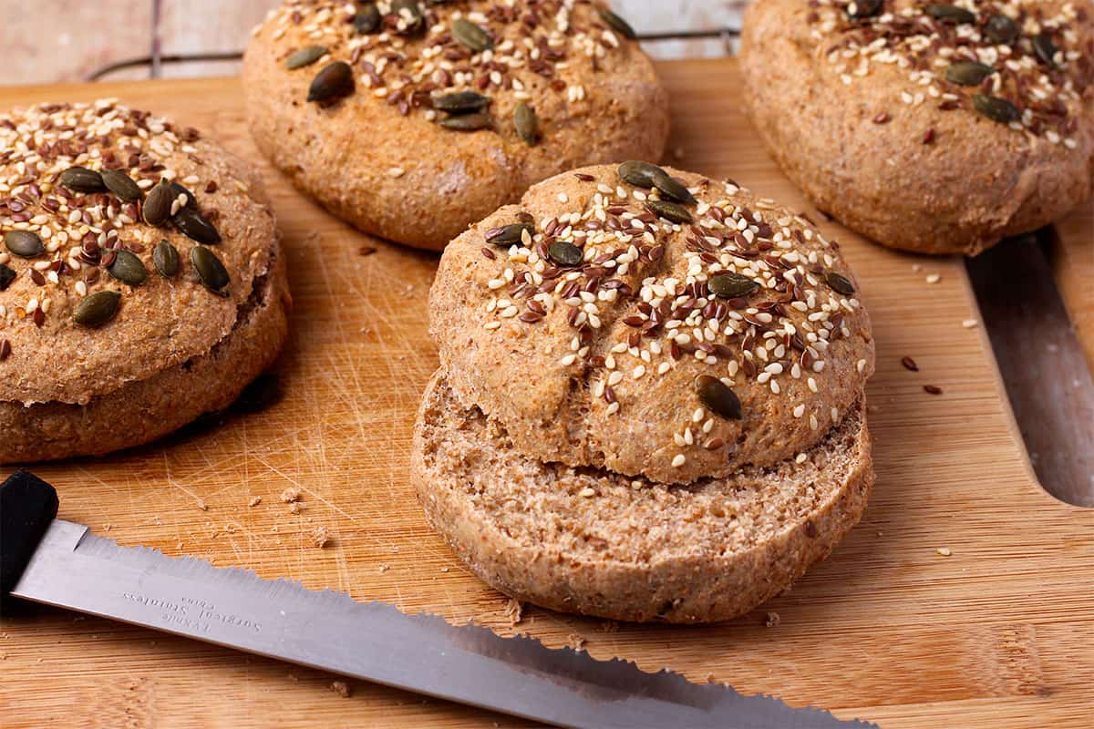 Whole wheat buns topped with seeds are sliced.