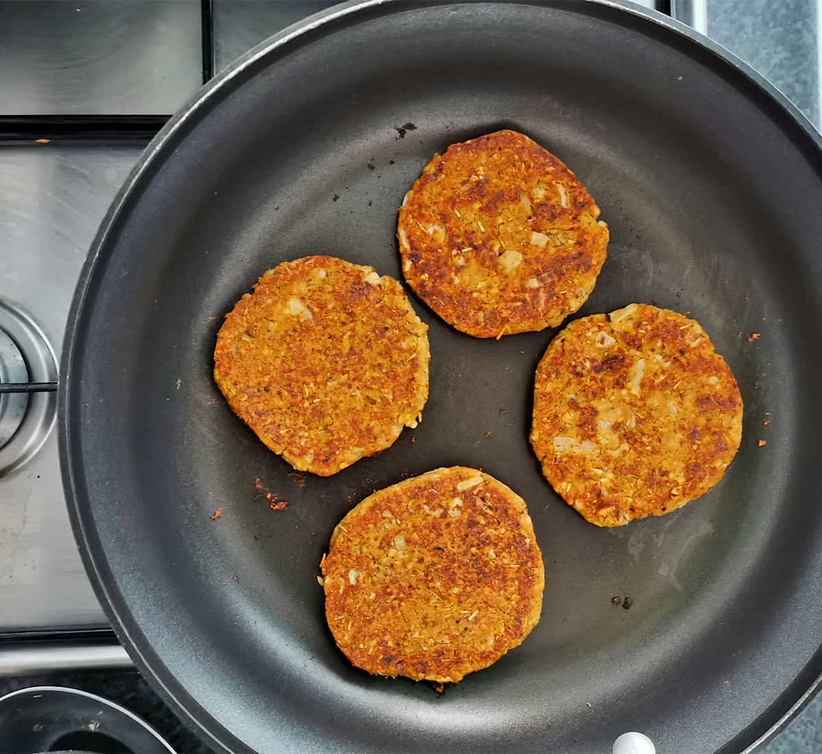 Tempeh vegan breakfast sausage patties are fried in a pan.