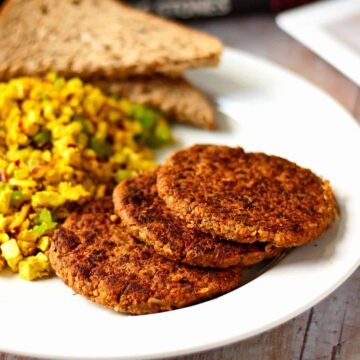 Tempeh breakfast sausage patties on a white plate with scrambled tofu.