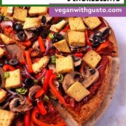A sliced veggie pizza with sweet potato crust on a pizza stone.